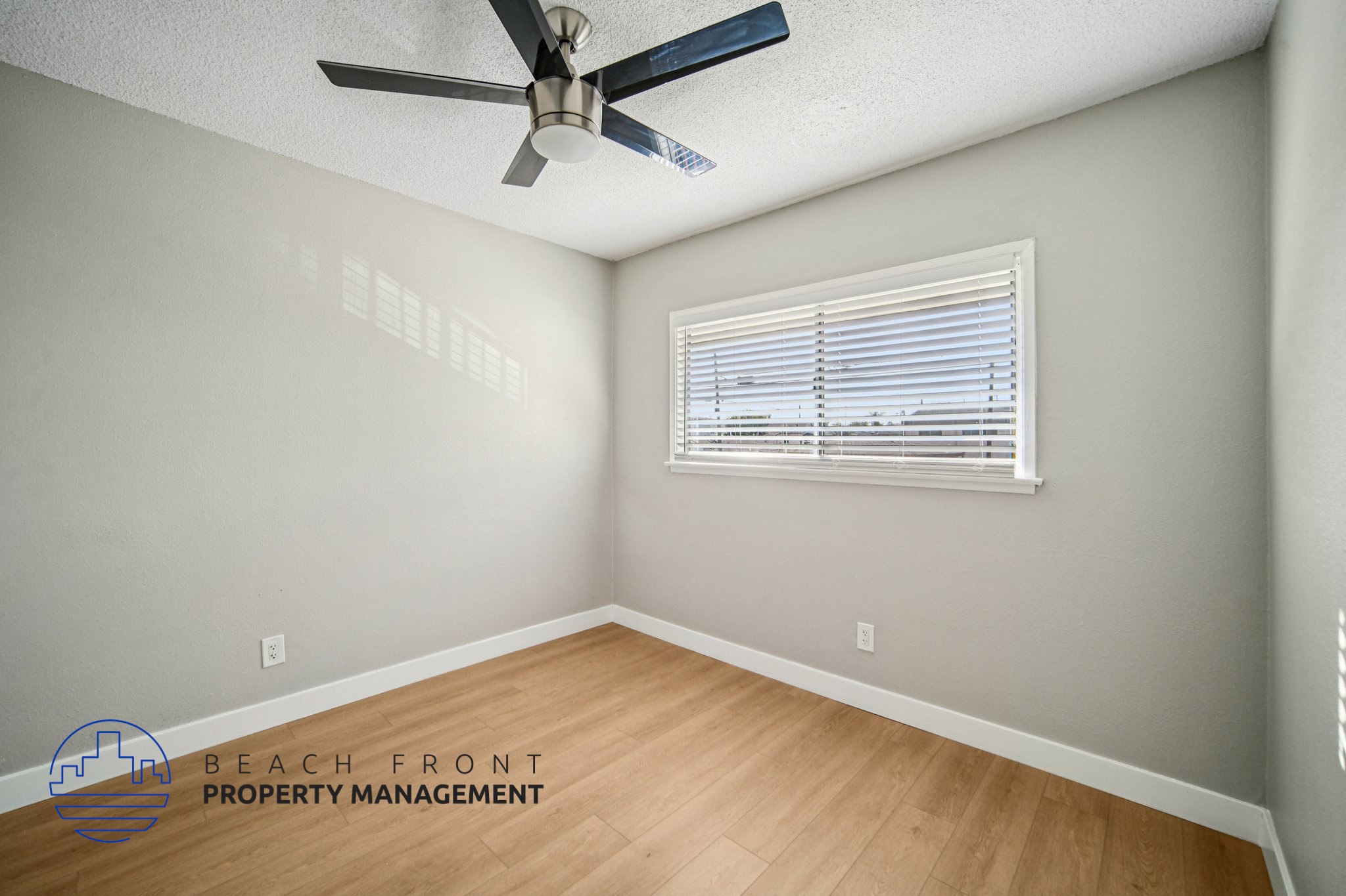 A room with a ceiling fan and a window with blinds.